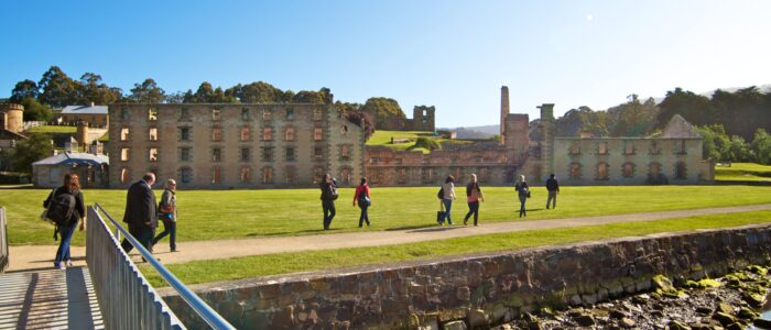 A group of people walking along a path towards some stone historic buildings