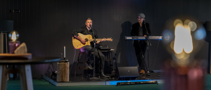 Joel Everard Music 1 2 people standing on stage, one holding a guitar singing the other looking towards him as he plays the keyboard
